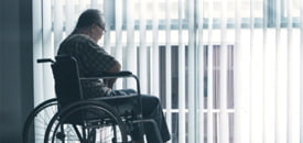 Picture of sad elderly man sitting in the wheelchair in a retirement home